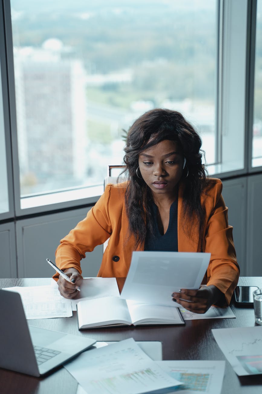 woman in orange jacket holding a paper