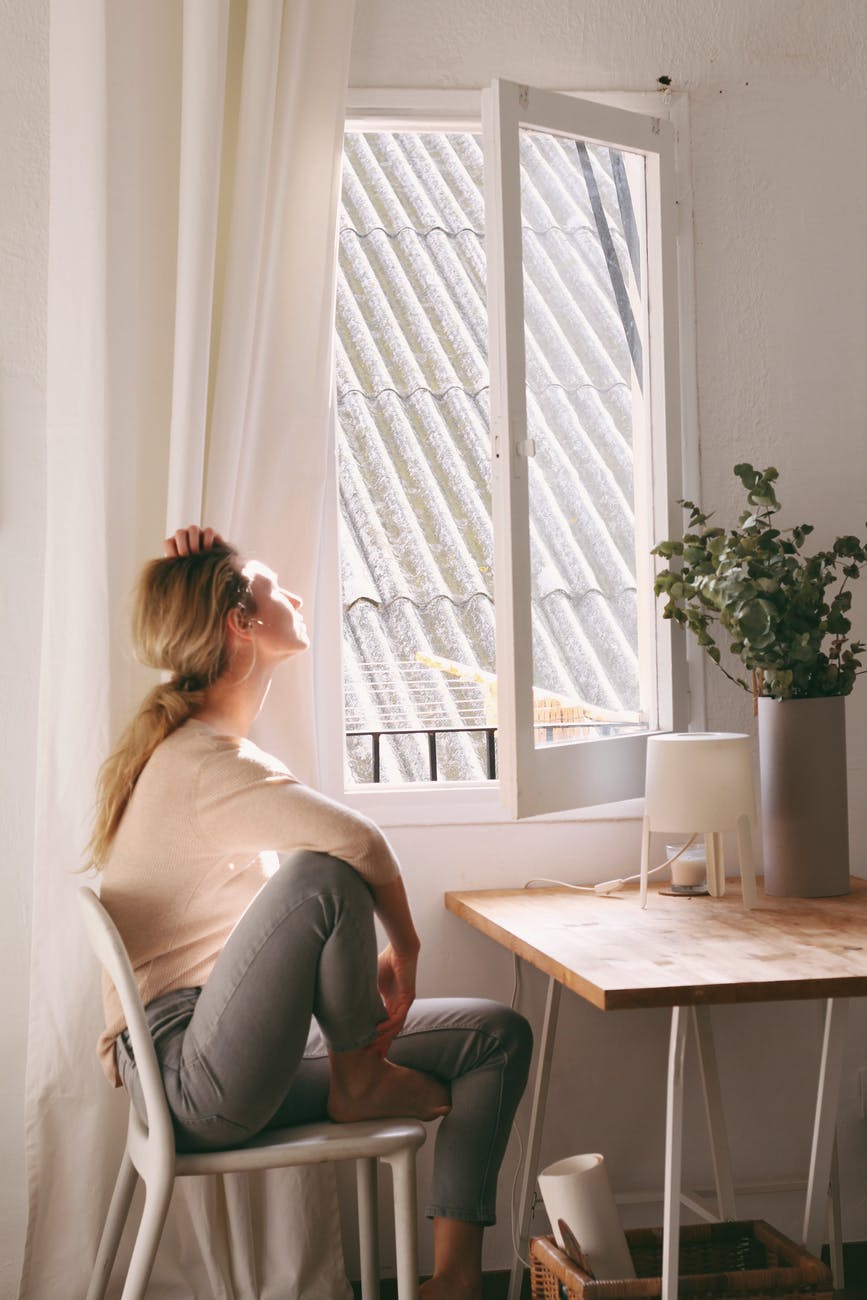 woman sitting on a chair next to a window smart money bro.