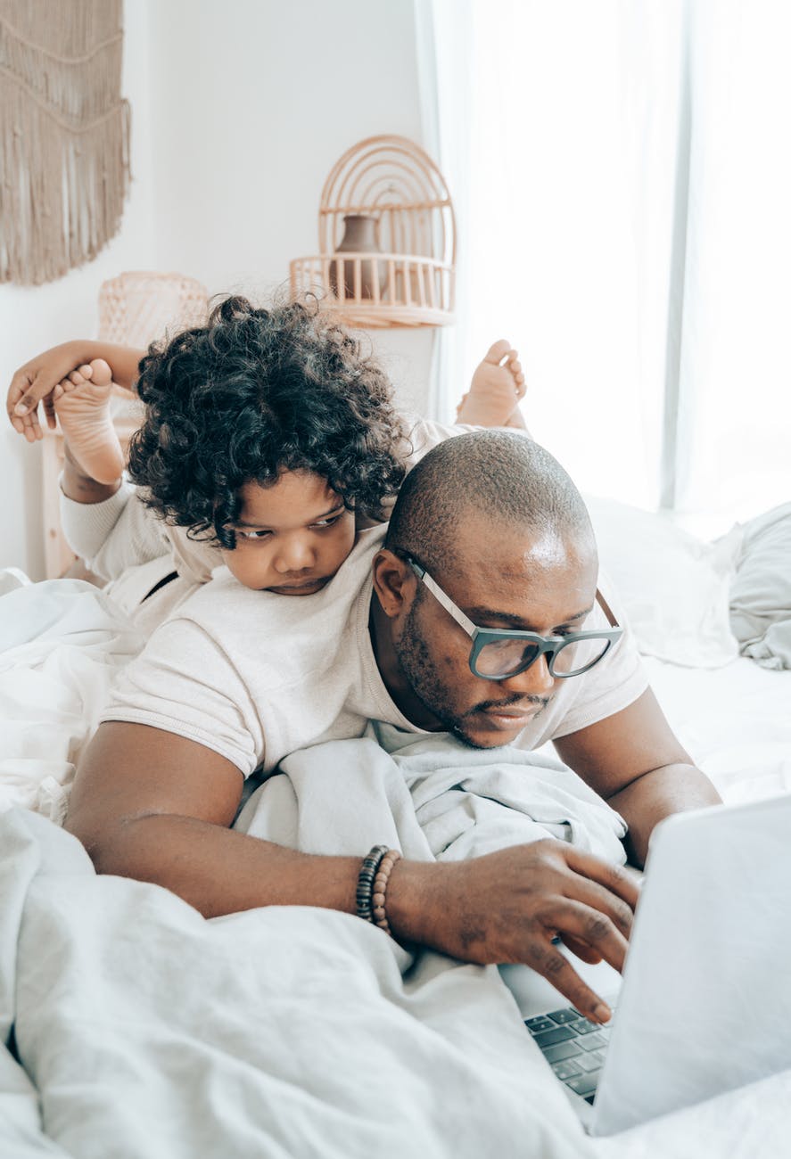 father working from home with child on his back, smart money bro