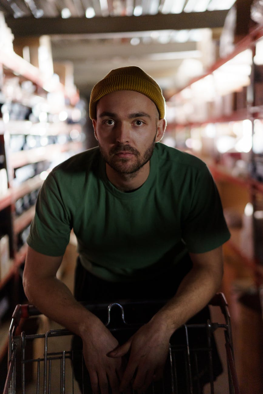 man in green crew neck t shirt and yellow knit cap sitting on chair, smart money bro