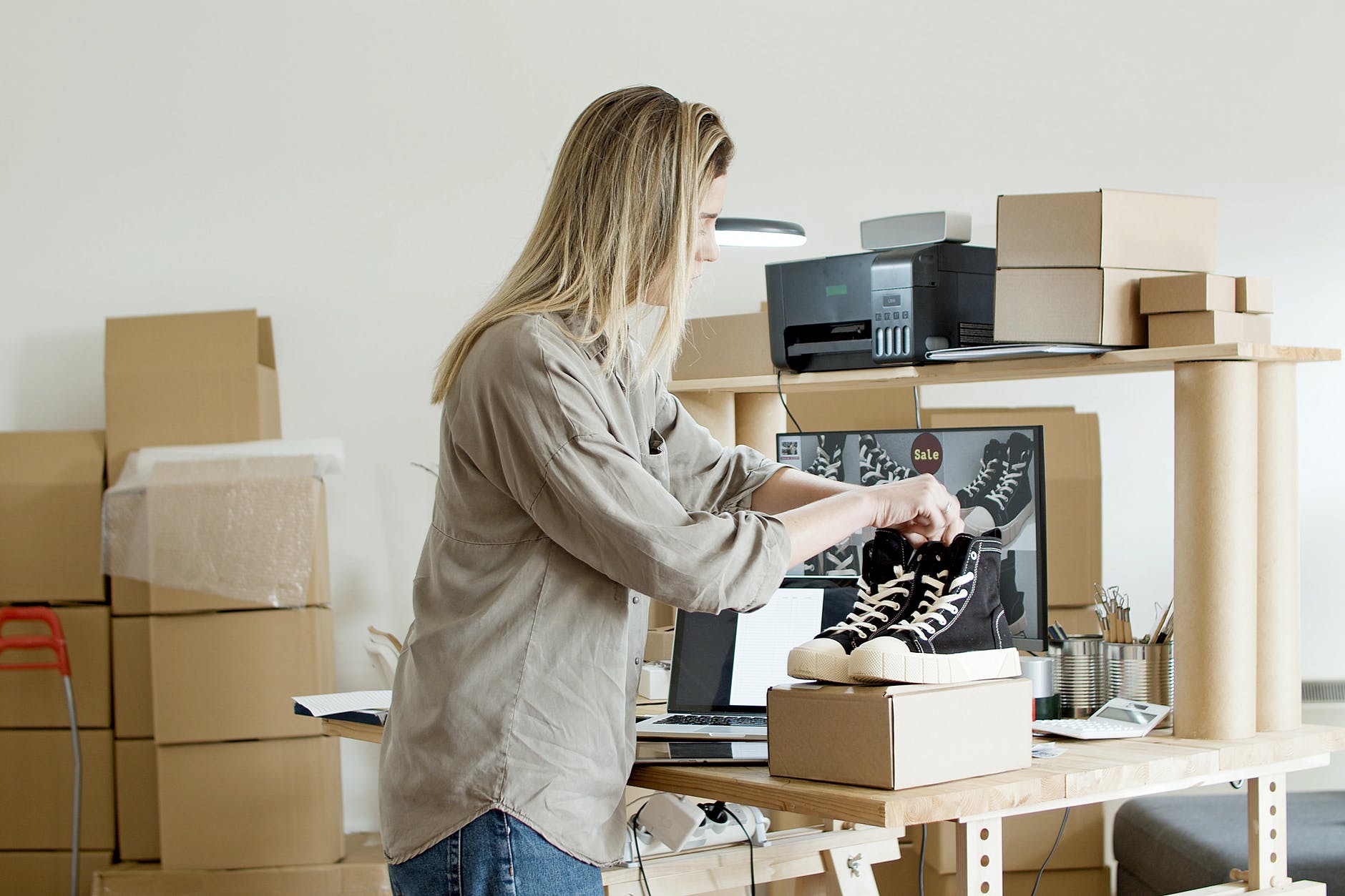 woman holding black shoes on top of the box, smart money bro